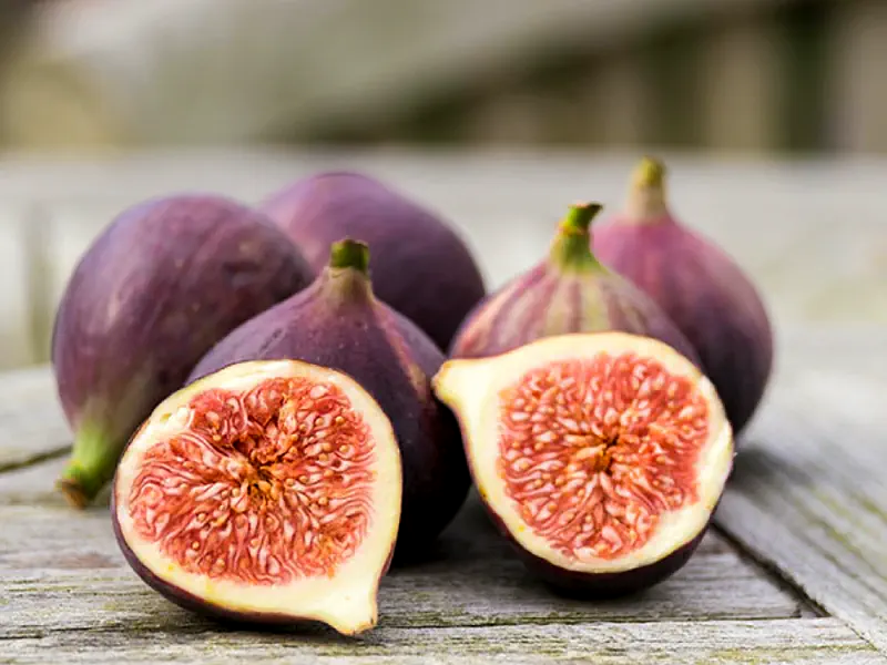 Whole and halved fresh figs on a wooden table