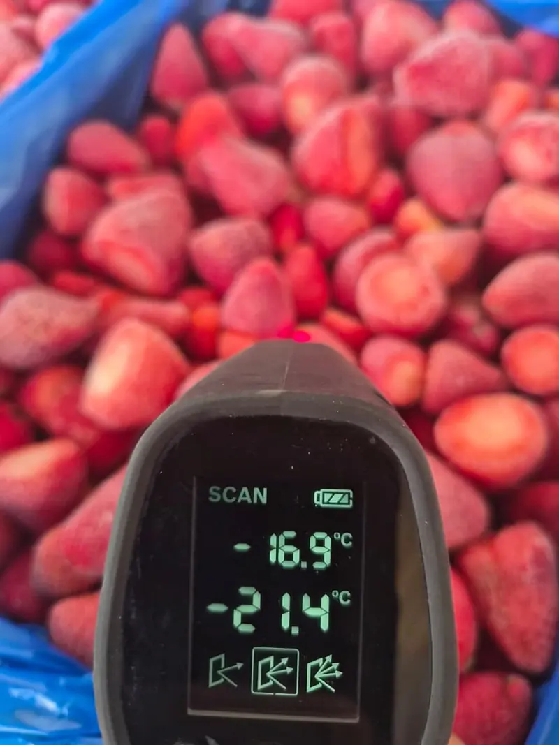An infrared thermometer checking the temperature of frozen strawberries
